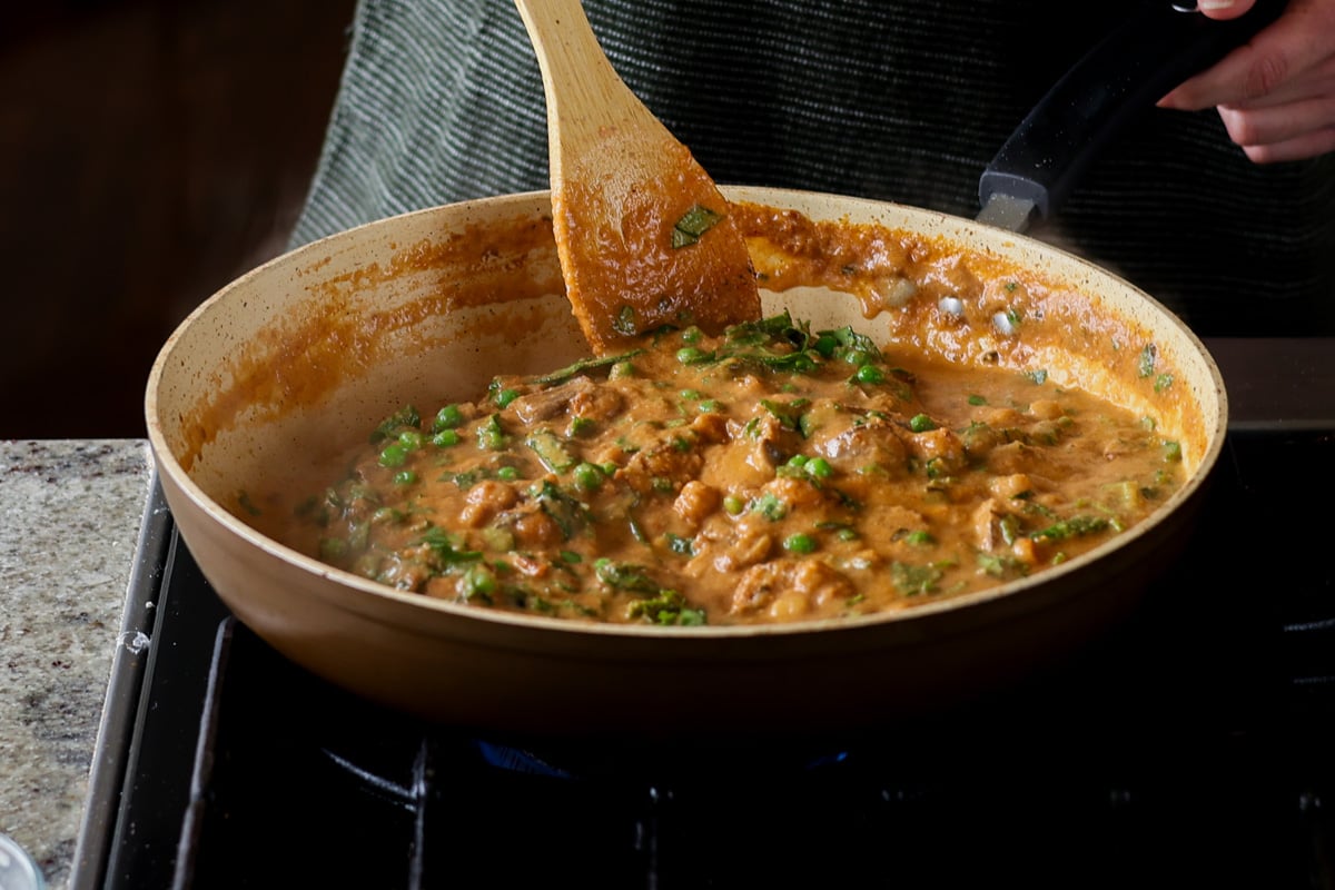 mixing peas into the sauce
