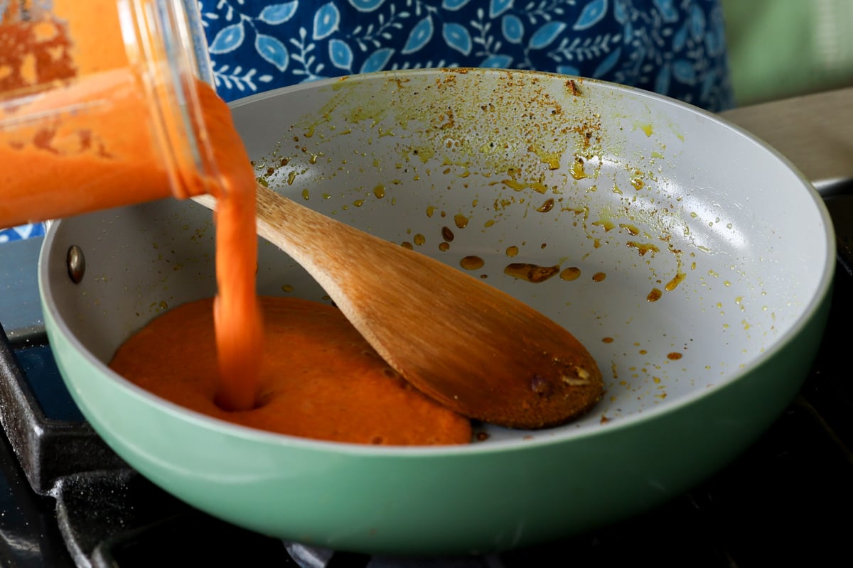 adding the spiced tomato soup back to the pan