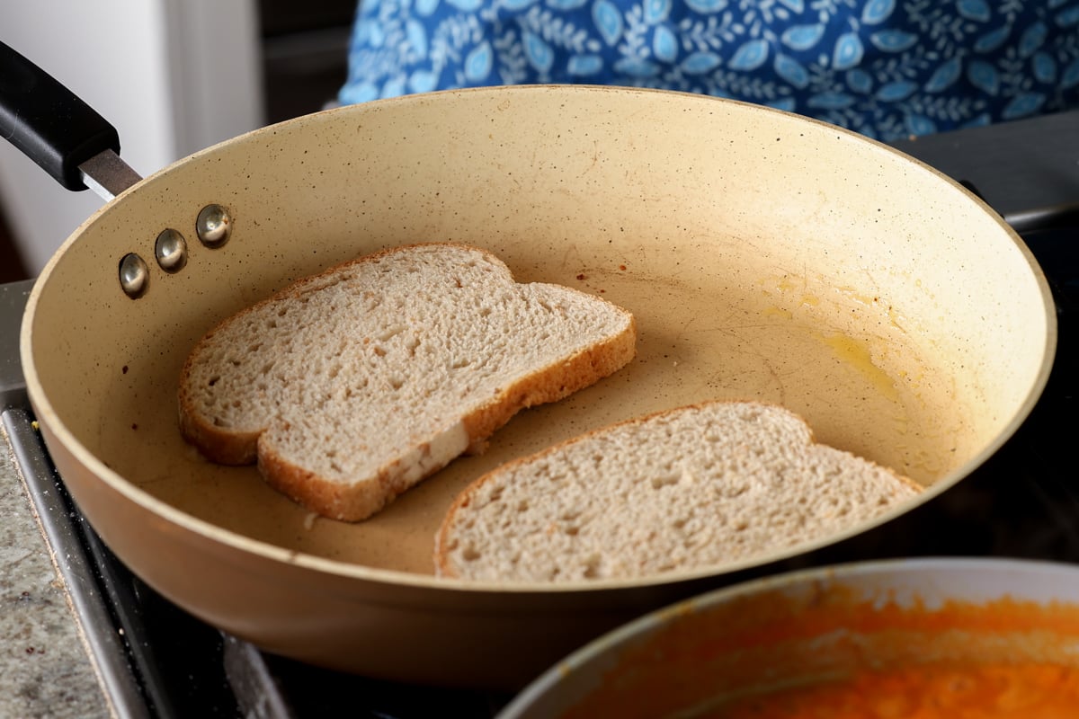 adding bread on top of the cheese shreds in the pan