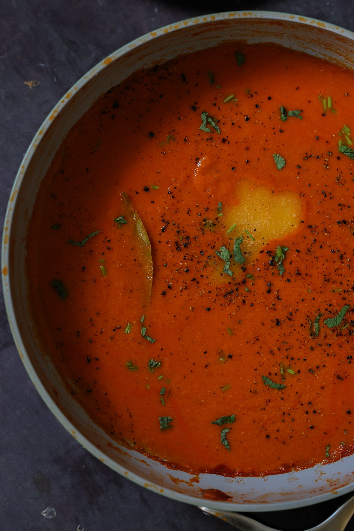 close-up of spiced tomato soup in the pan with garnishes