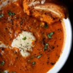 bowl of spiced tomato soup with garnishes added the grilled cheese