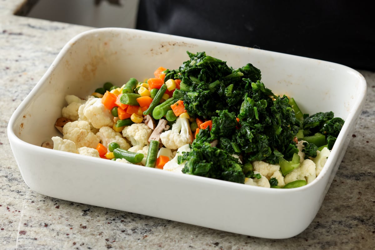 adding baby greens to the casserole dish