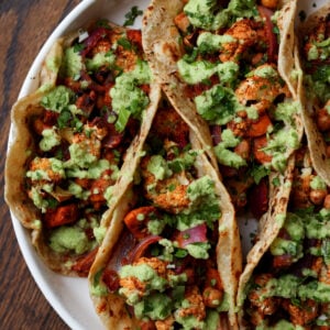 cauliflower sweet potato tacos on a plate with coconut chutney and garnishes