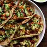 cauliflower sweet potato tacos on a plate next to a side salad