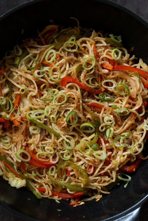 Hakka noodles in the pan after garnishing with scallions