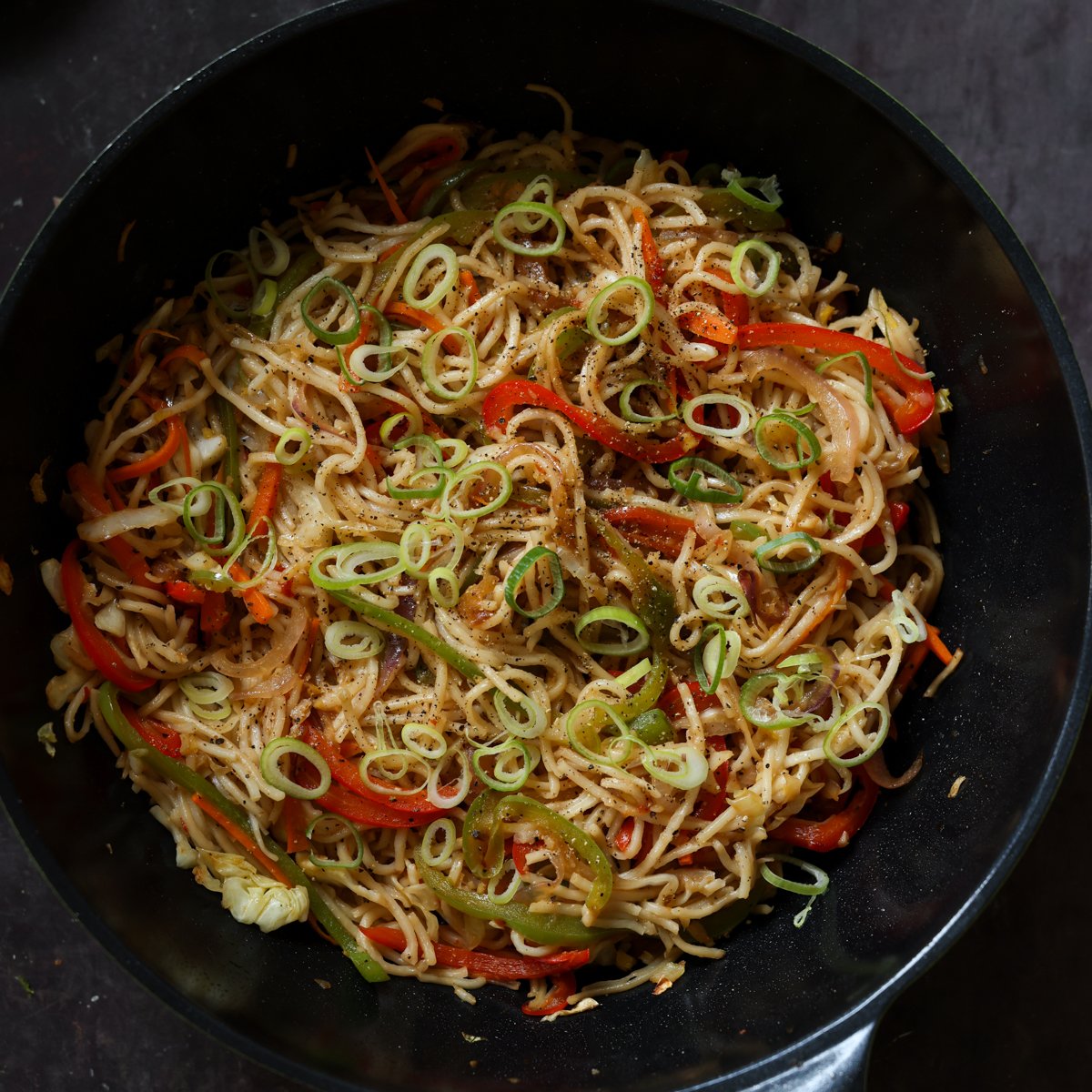 Hakka noodles tossed in veggies and sauce in the pan