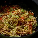 Hakka noodles in the pan after garnishing with scallions