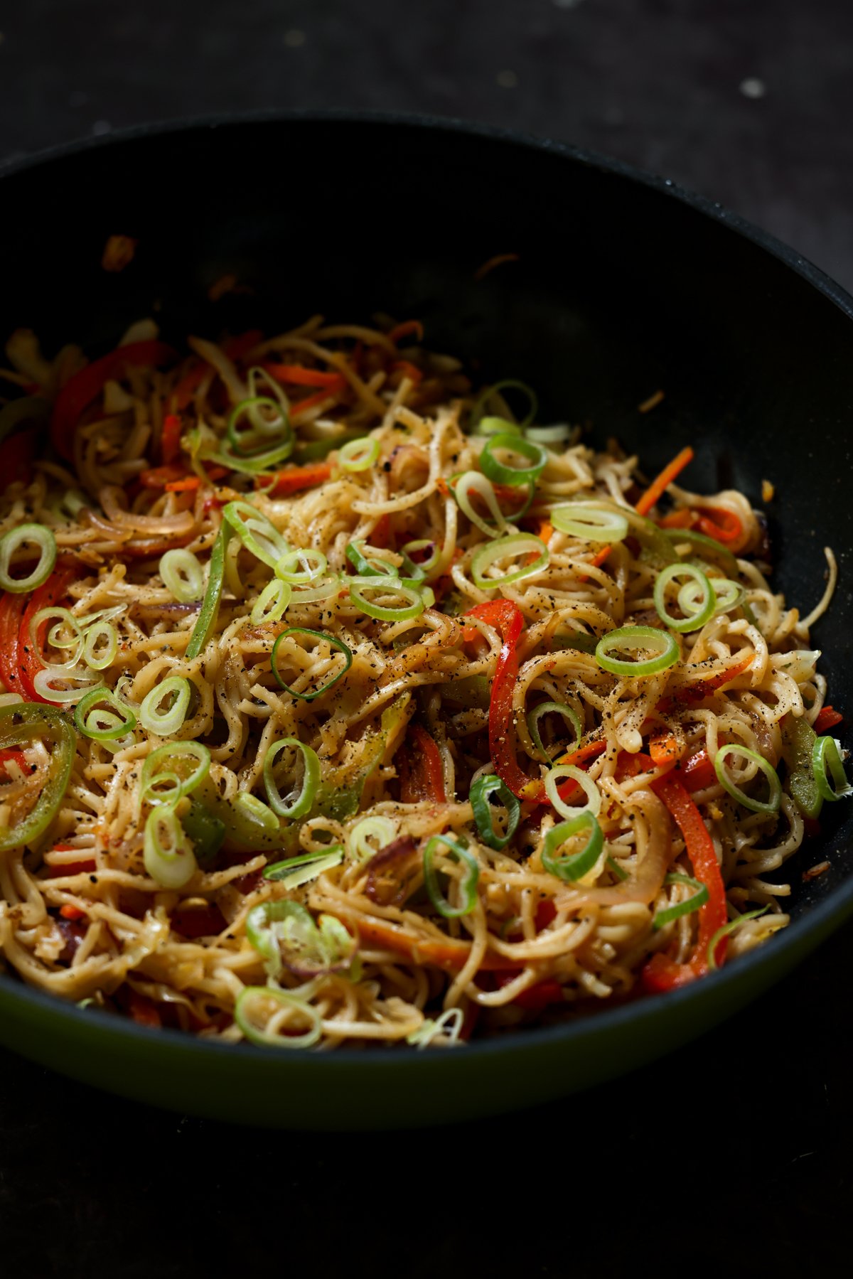 Hakka noodles in the pan after garnishing with scallions