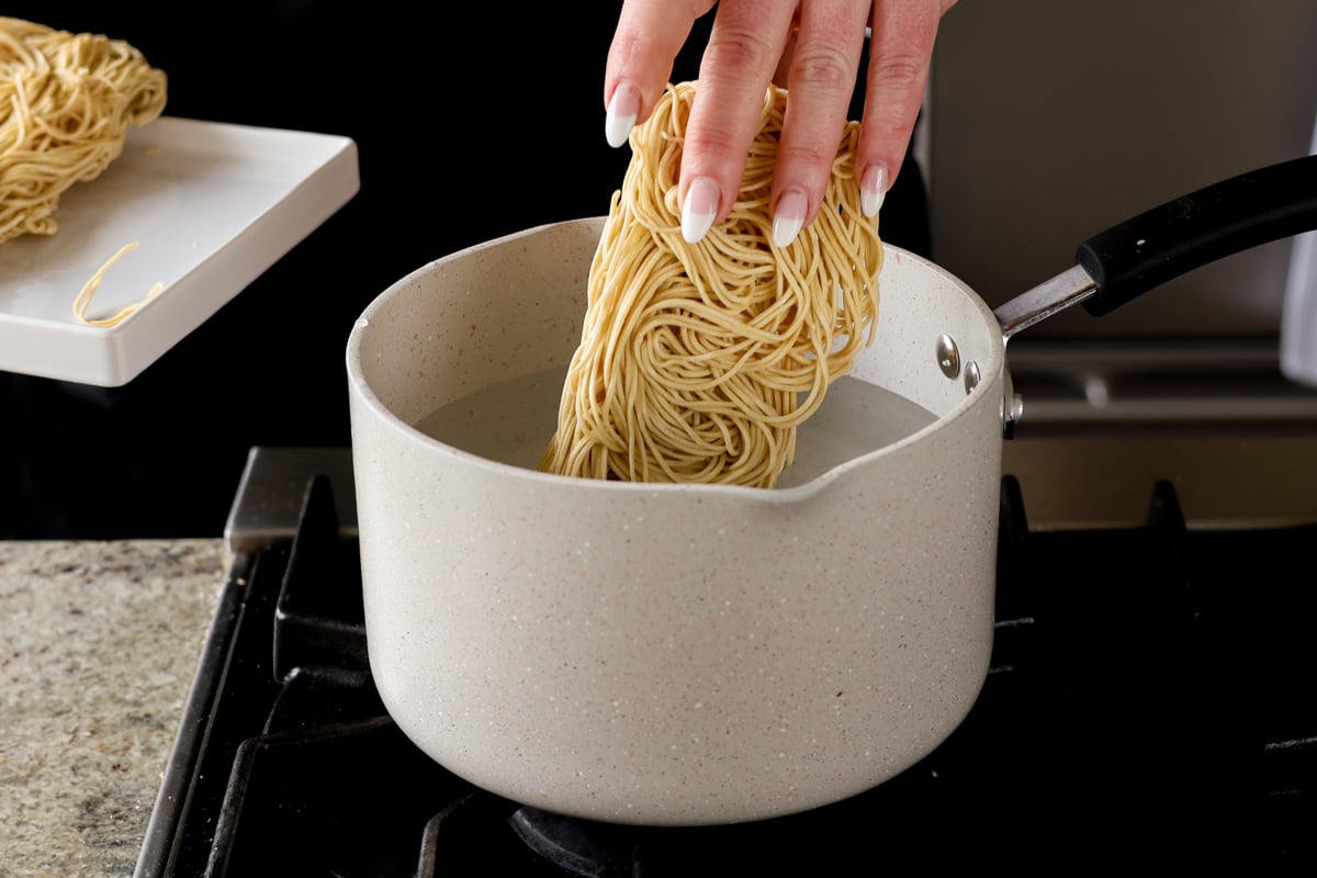 adding Hakka noodles to boiling water