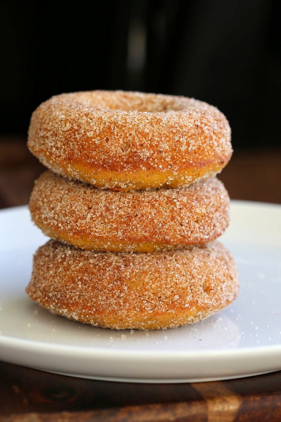Vegan Pumpkin Donuts dusted with Cinnamon Sugar on a white plate