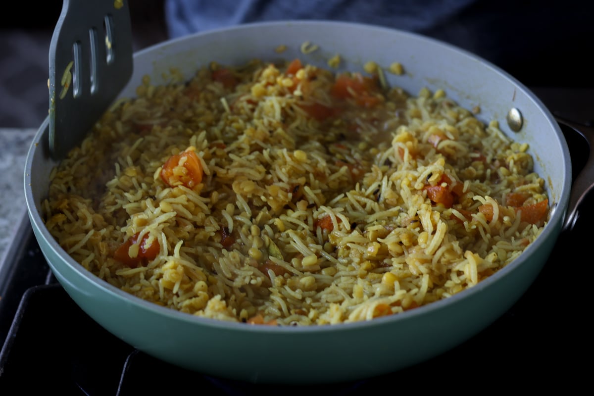 fluffing the cooked khichdi in the pan