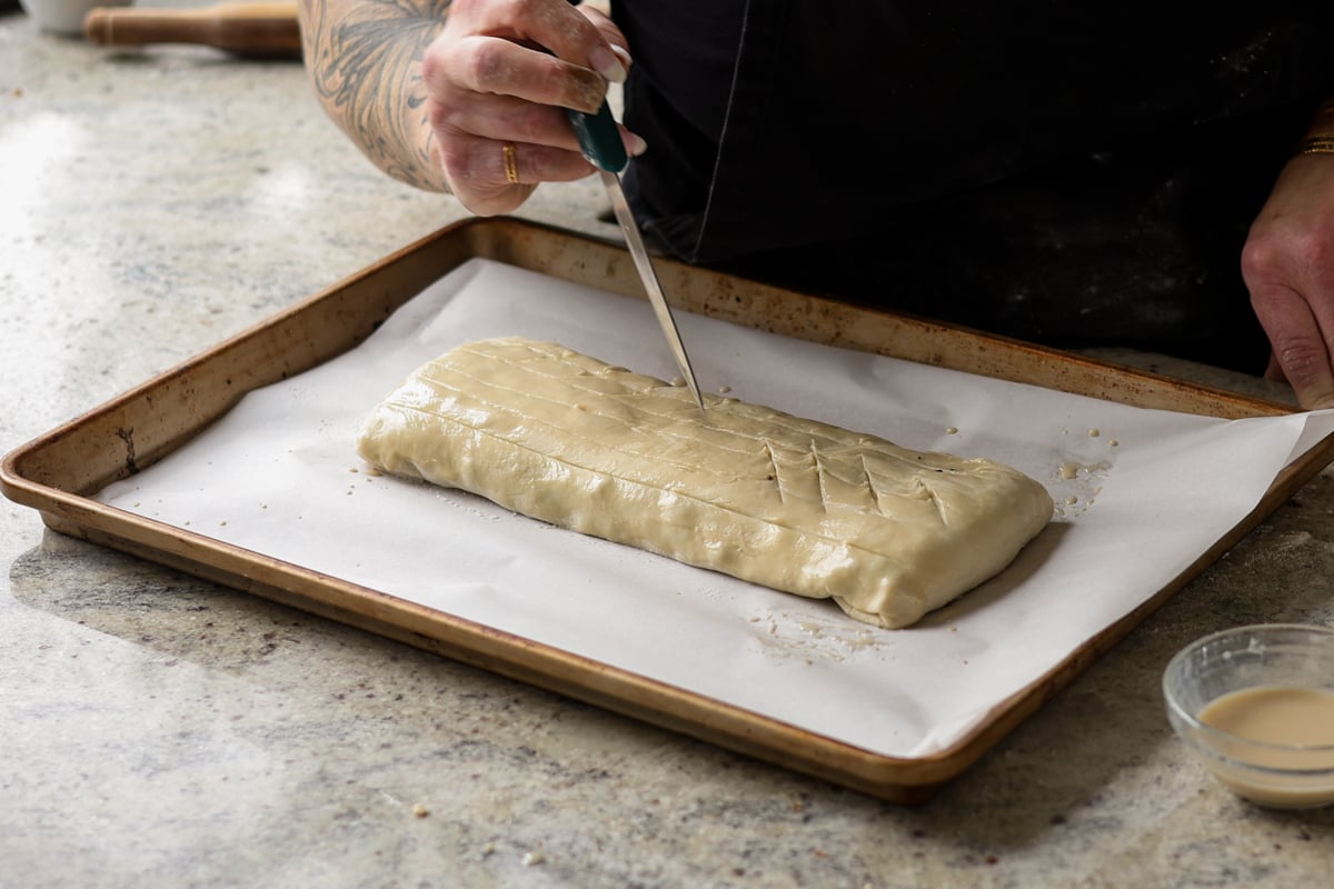 slicing decorative vents into the puff pastry with scissors
