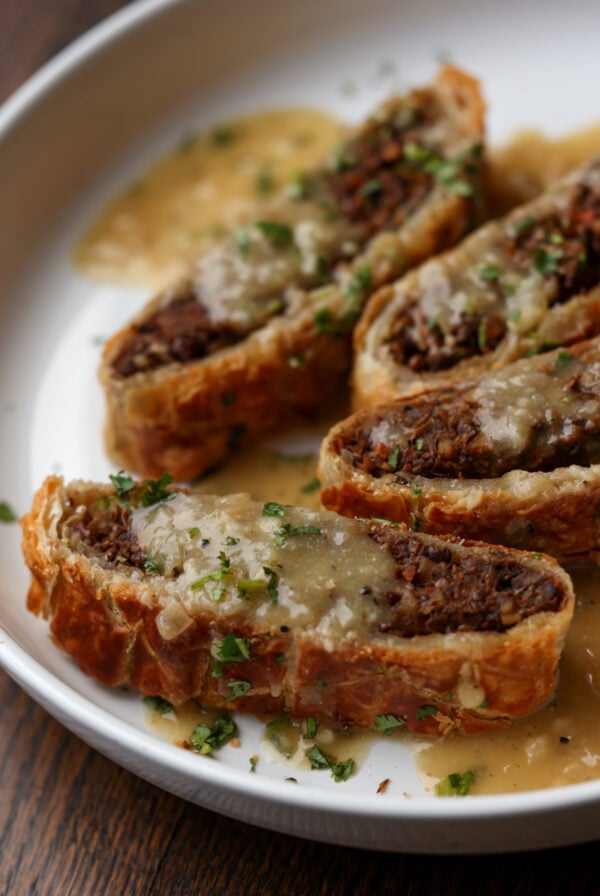 angled shot of lentil wellington on a plate with gravy to show more texture