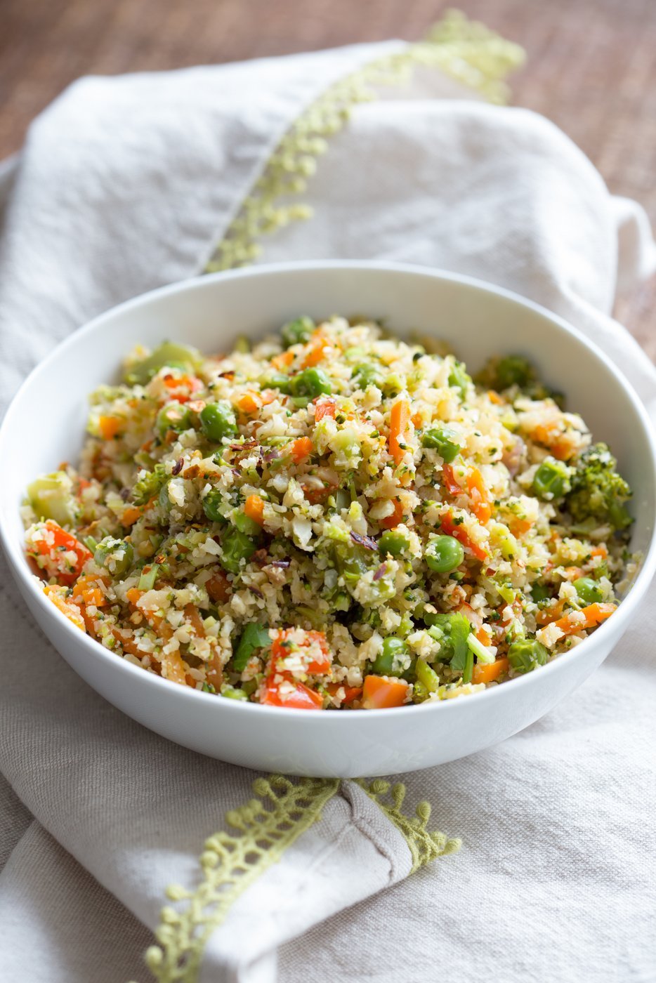 Vegan Cauliflower Fried Rice in white bowl over cotton napkin