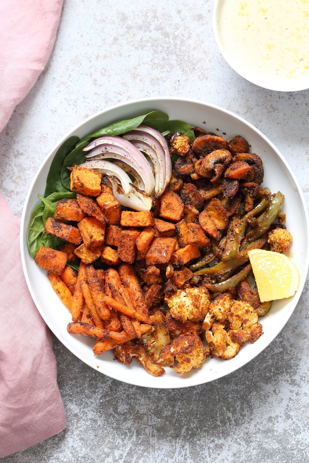 Cajun Roasted Vegetable Bowl with Garlic Sauce. Mushrooms, Cauliflower, Sweet Potato, Peppers, Onions, tossed in cajun spice blend and roasted. Serve in a bowl with crunchy greens and creamy garlic sauce or make wraps or tacos. #veganricha #Vegan #Glutenfree #Soyfree #Recipe. Can be nut-free. | VeganRicha.com
