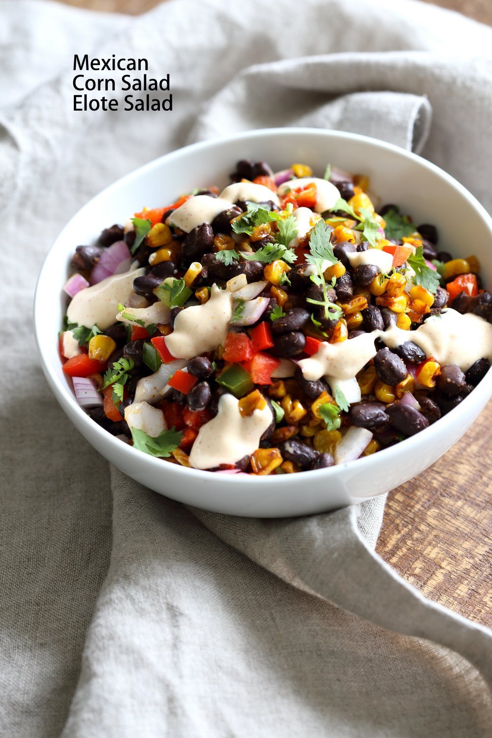 Mexican street corn salad in a white bowl with grey napkin