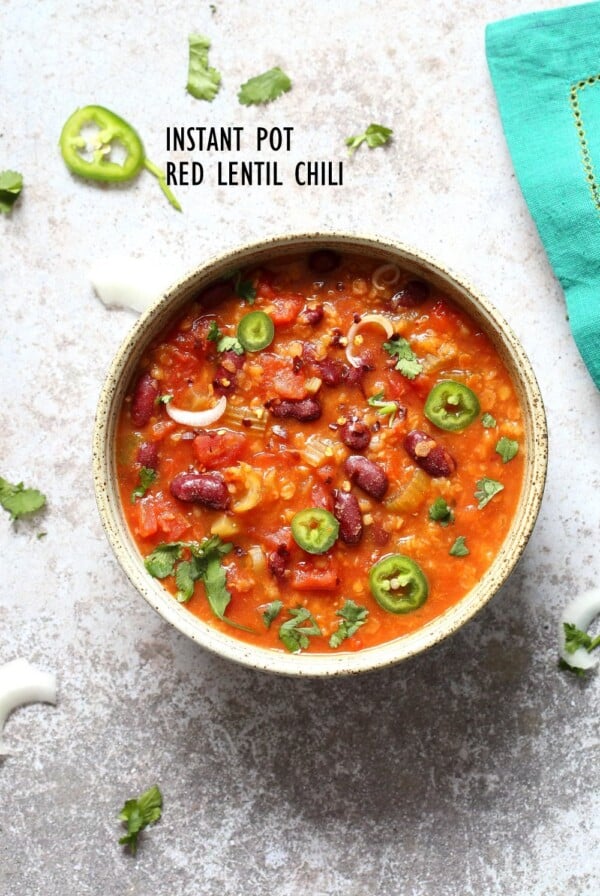 A bowl of instant pot red lentil chili on a white background with a turquoise napkin