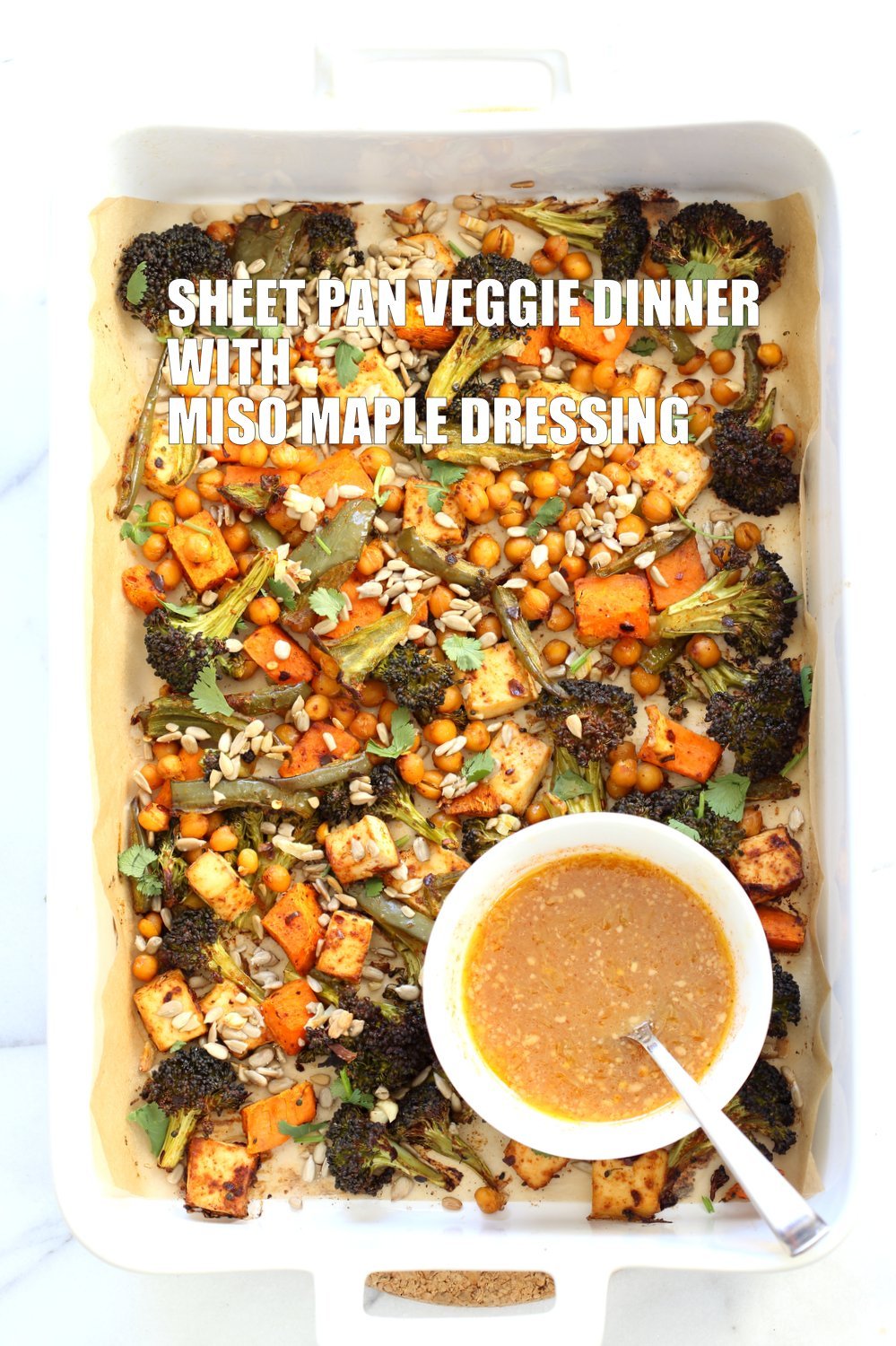 Sheet pan roasted veggies and chickpeas in large baking dish with miso maple dressing bowl on bottom left for a weekday Sheet pan Veggie Dinner
