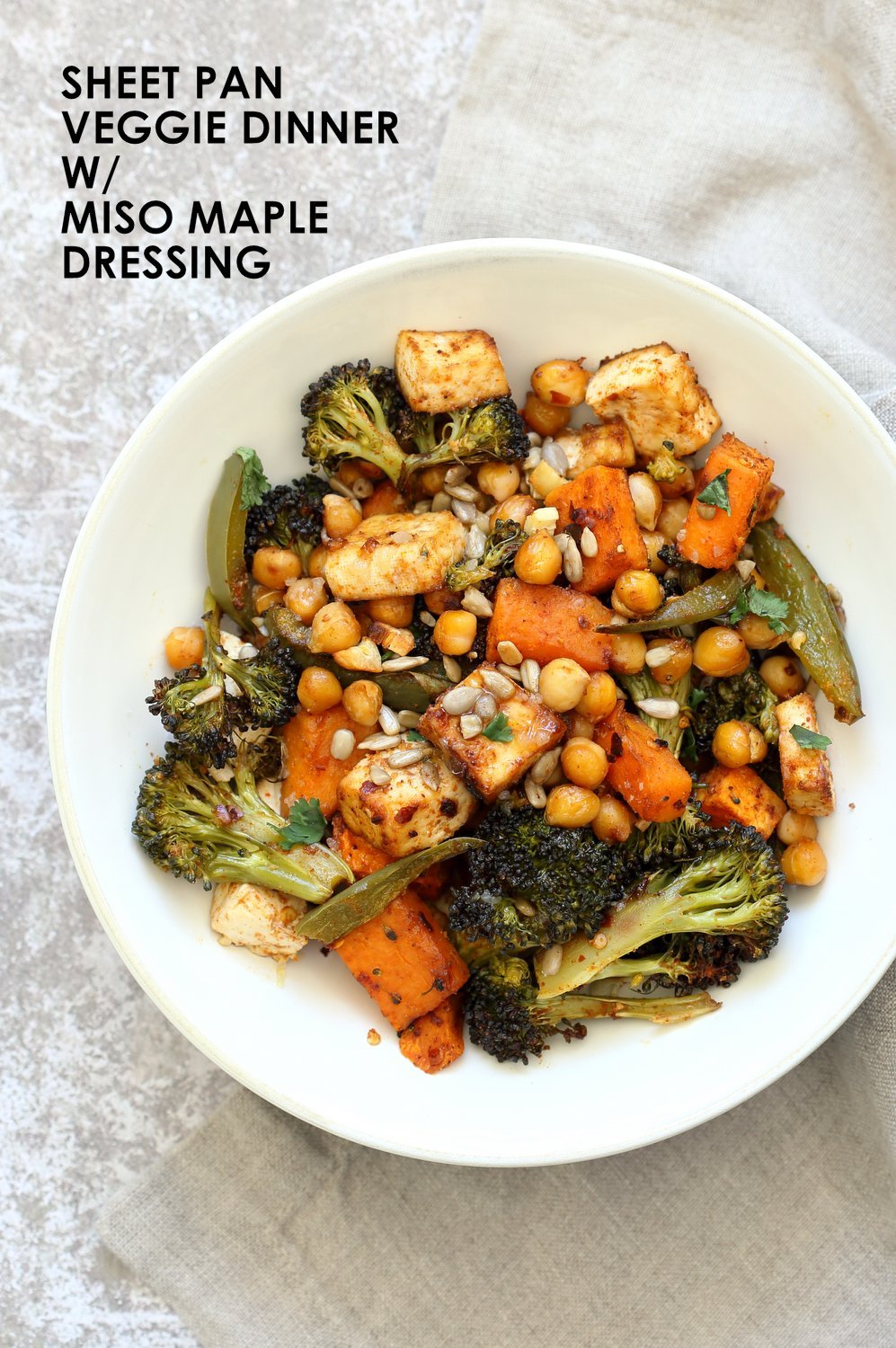 Sheet Pan Veggie Dinner with Roasted Veggies, Chickpeas, Tofu in a white Bowl over grey napkin and concrete