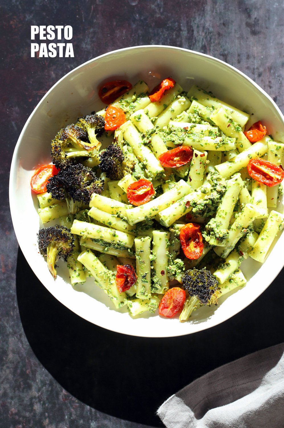 Large While Bowl with Vegan Pesto Pasta with Ziti, roasted cherry tomatoes and Charred broccoli on black stone