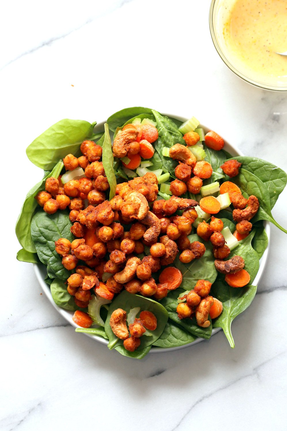 Our Sriracha Chickpeas Spinach Bowl getting assembled in a while bowl on marble