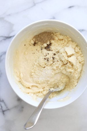 Making our Vegan Malai Burfi- Mixing almond flour and cardamom in a white bowl