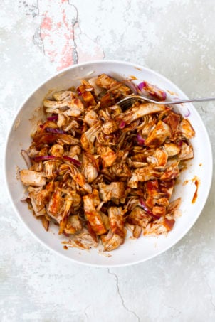 Shredded Jackfruit mixed with bbq sauce and bbq seasoning in a white bowl for our Vegan Pulled Jackfruit Sandwiches
