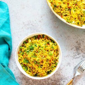 A bowl of curry fried rice on a work top with forks next to it