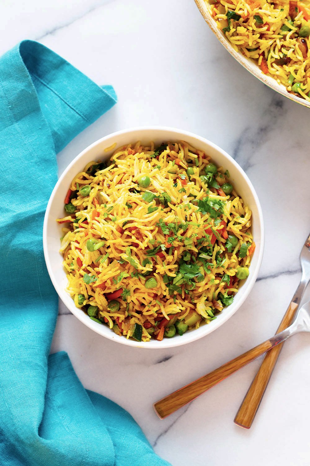 Top down shot of curry fried rice in a bowl with forks on a work surface