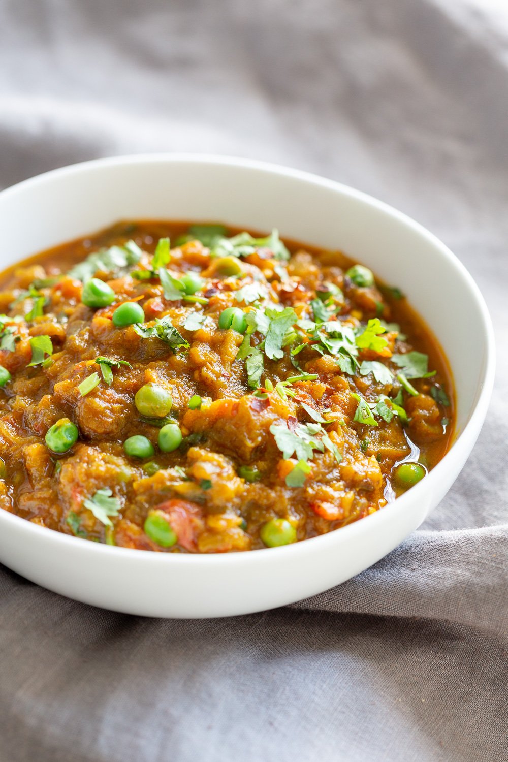 Instant Pot Baingan Bharta - Indian Spiced mashed eggplant in a white bowl, side view, on a grey napkin