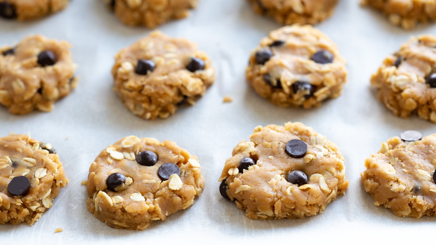 Vegan Peanut butter Oatmeal Chocolate chip Cookies on a parchment lined baking sheet