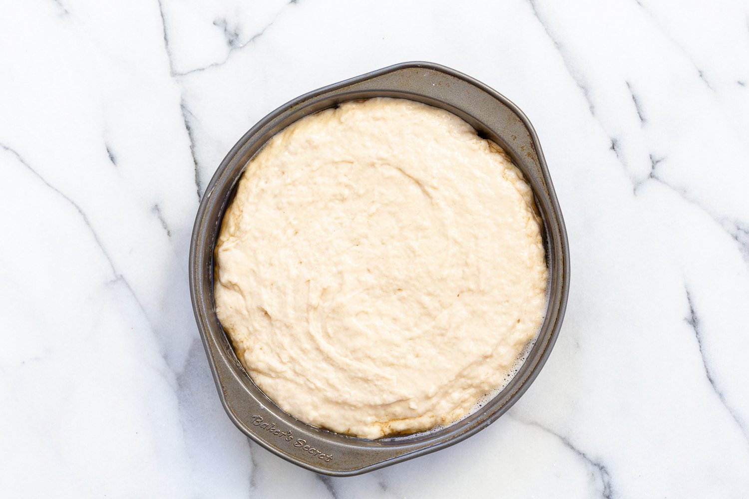 Cake Batter over pear slices in a metal cake pan for Our Vegan Pear Upside Down Cake