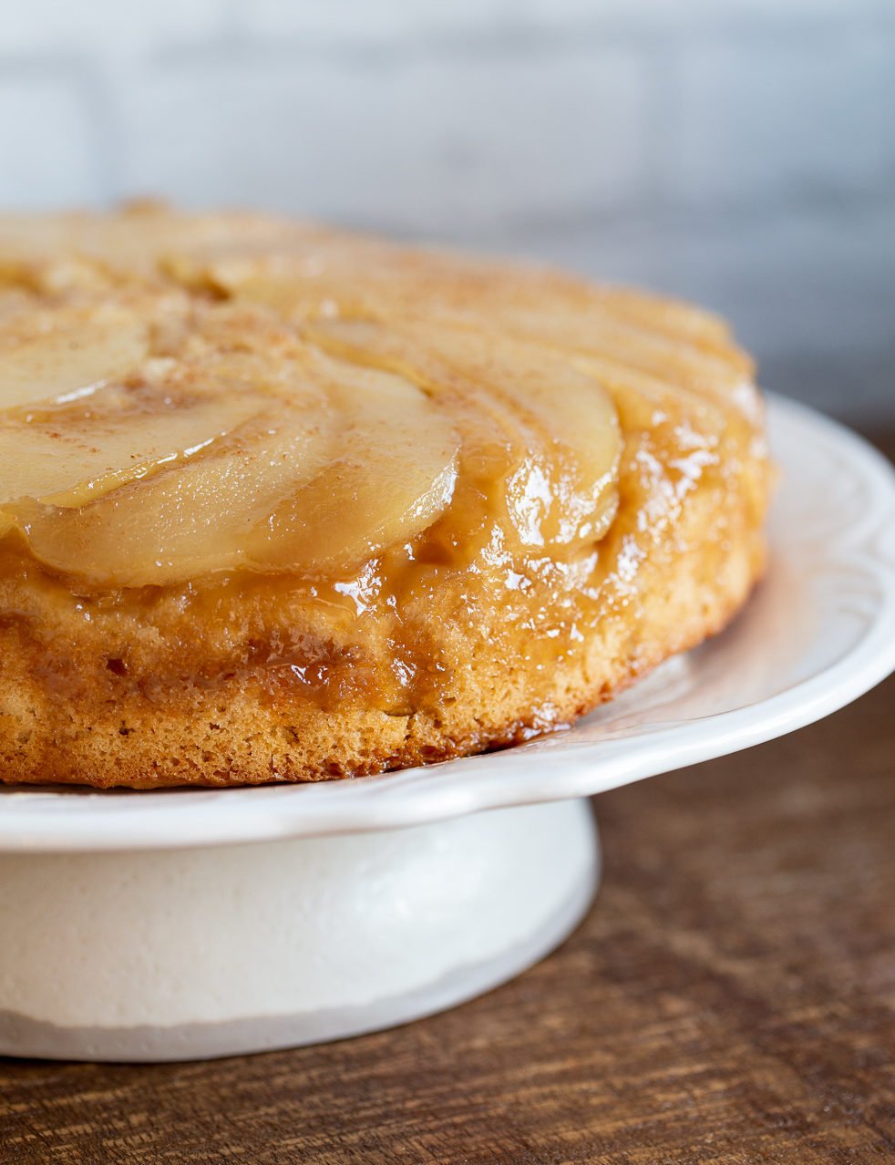 Our Vegan Pear Upside Down Cake on a white cake stand