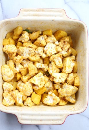 Our Vegan Baked Aloo Gobi Spiced Potatoes and Cauliflower ingredients mixed and ready to bake in a baking dish
