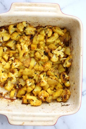 Our Vegan Baked Aloo Gobi Spiced Potatoes and Cauliflower in a white and red stoneware baking dish