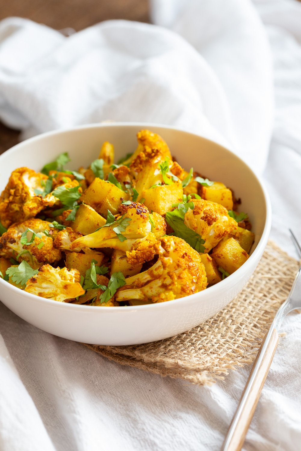 Vegan Aloo Gobi in a white bowl over white napkin