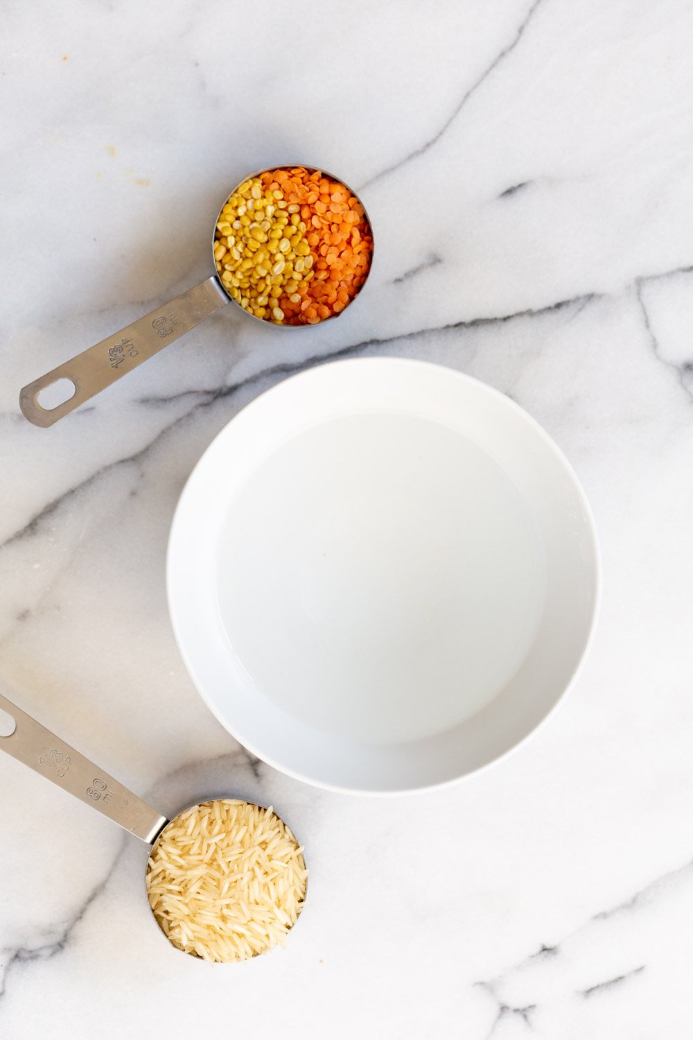Instant Pot Kitchari overhead shot of basmati rice dal split mung beans and red lentils next to a bowl of water