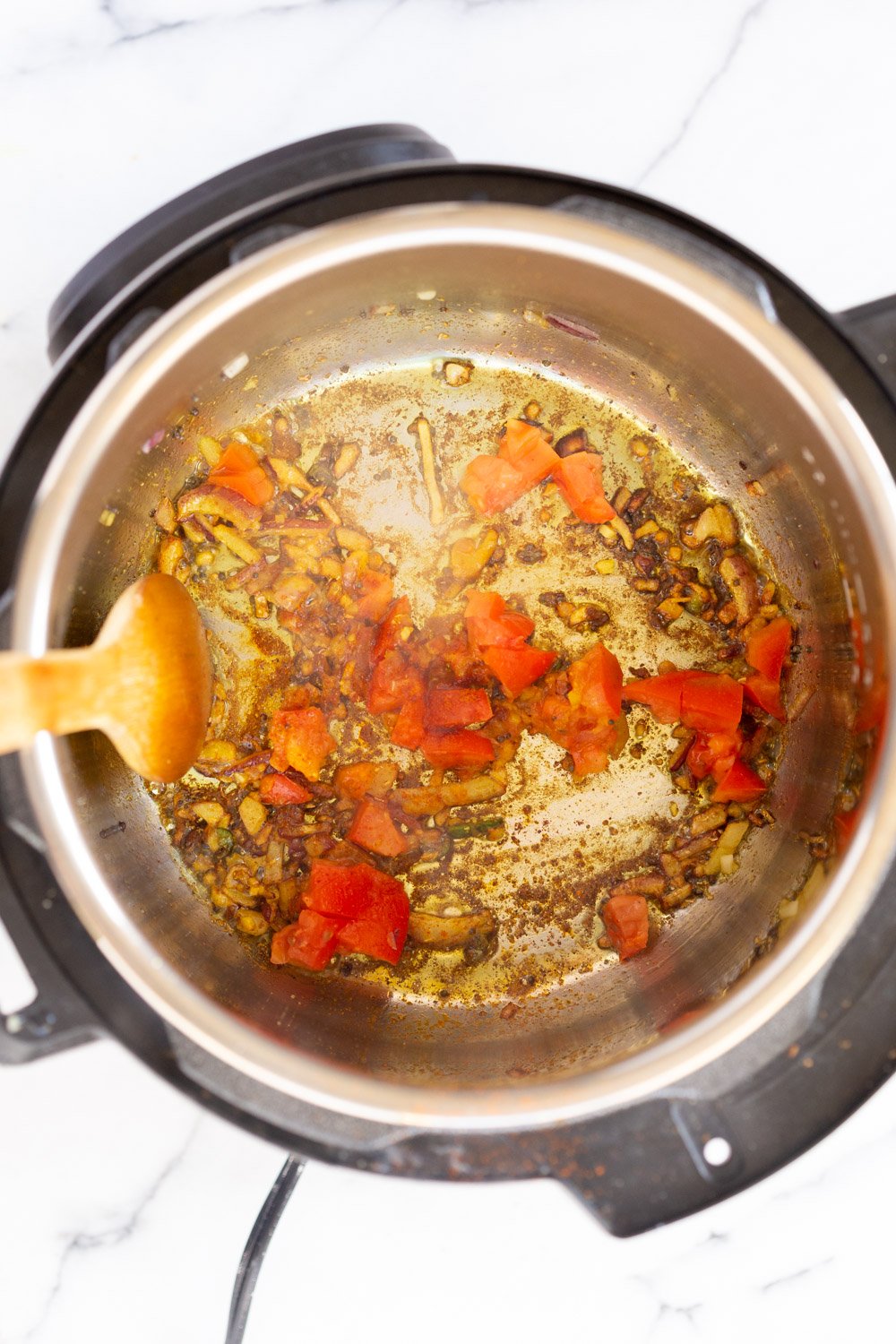 Instant Pot Kitchari  onions, garlic and spices being fried in an Instant Pot to make Kitchari