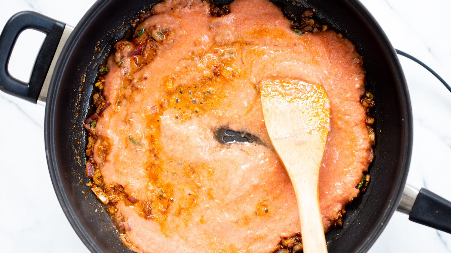 TomatoCashew sauce getting cooked with spices in a black skillet for Our Vegan Tofu Amritsari Masala Sauce