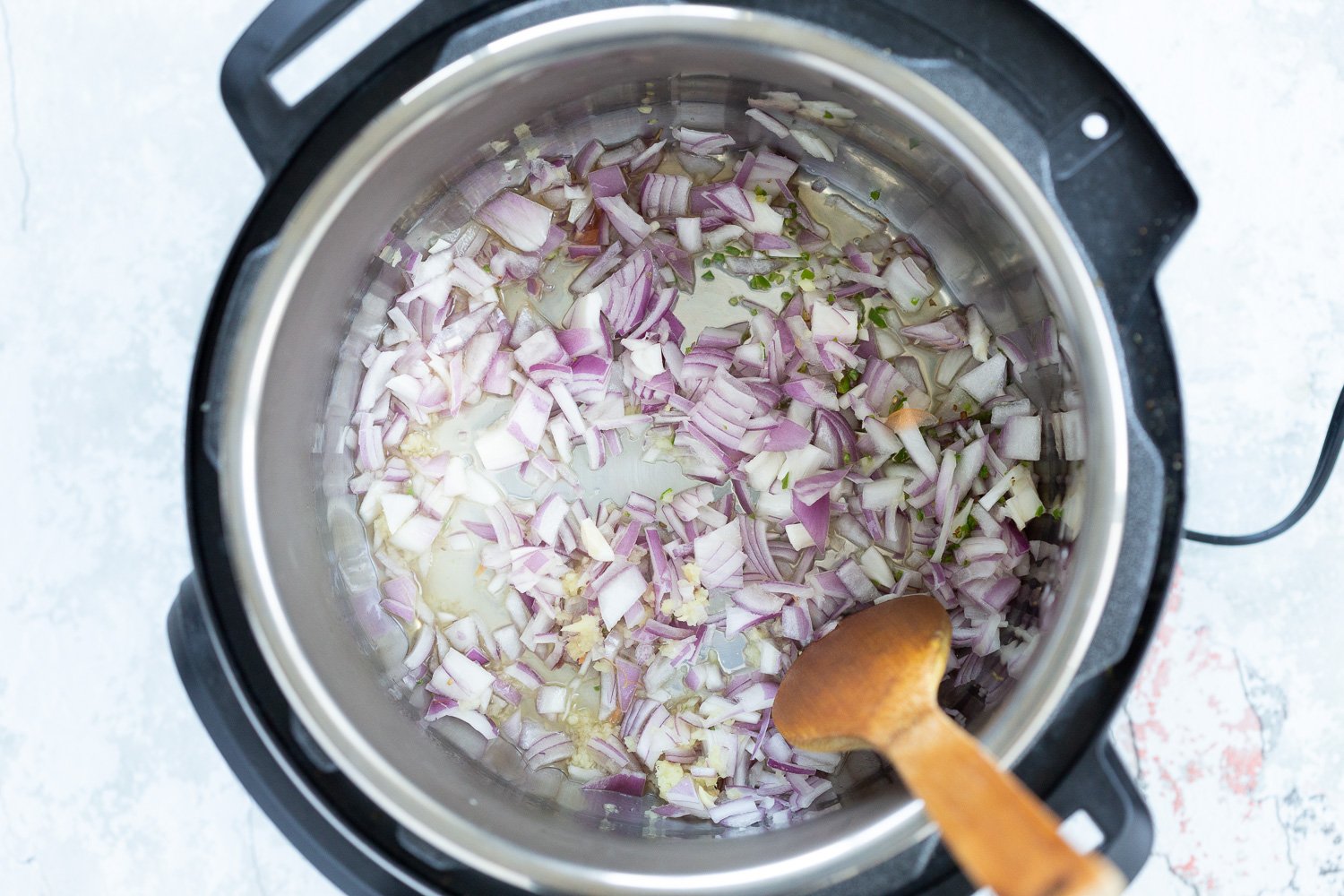 Onion, garlic, ginger getting cooked in an Instant Pot for Our Vegan Lentil Soup