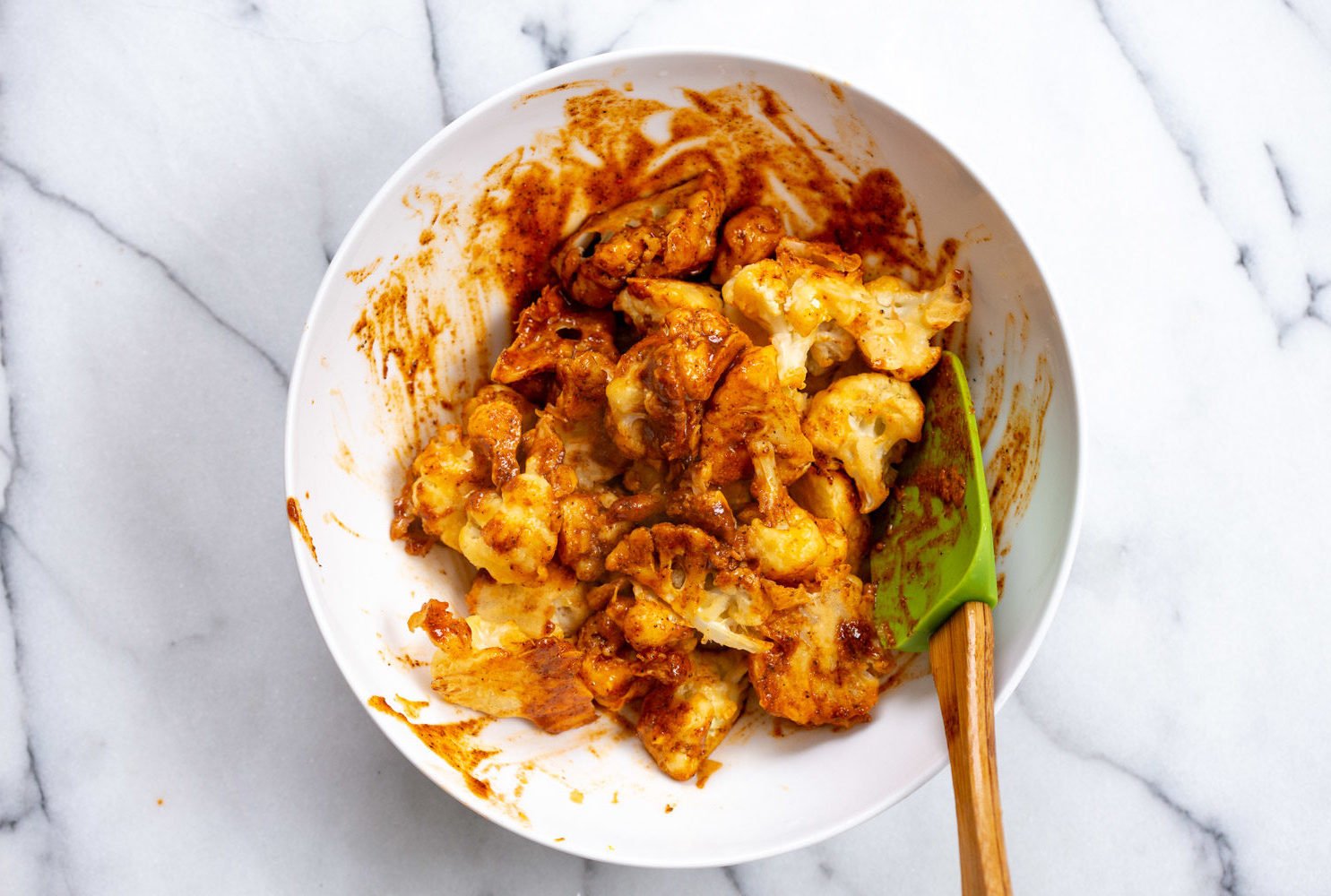 Our Baked Nashville Hot Cauliflower Wings mixed with Nashville hot sauce in a white bowl