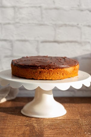 Our Vegan Gluten free Vanilla Cake getting layered over another cake with chocolate frosting