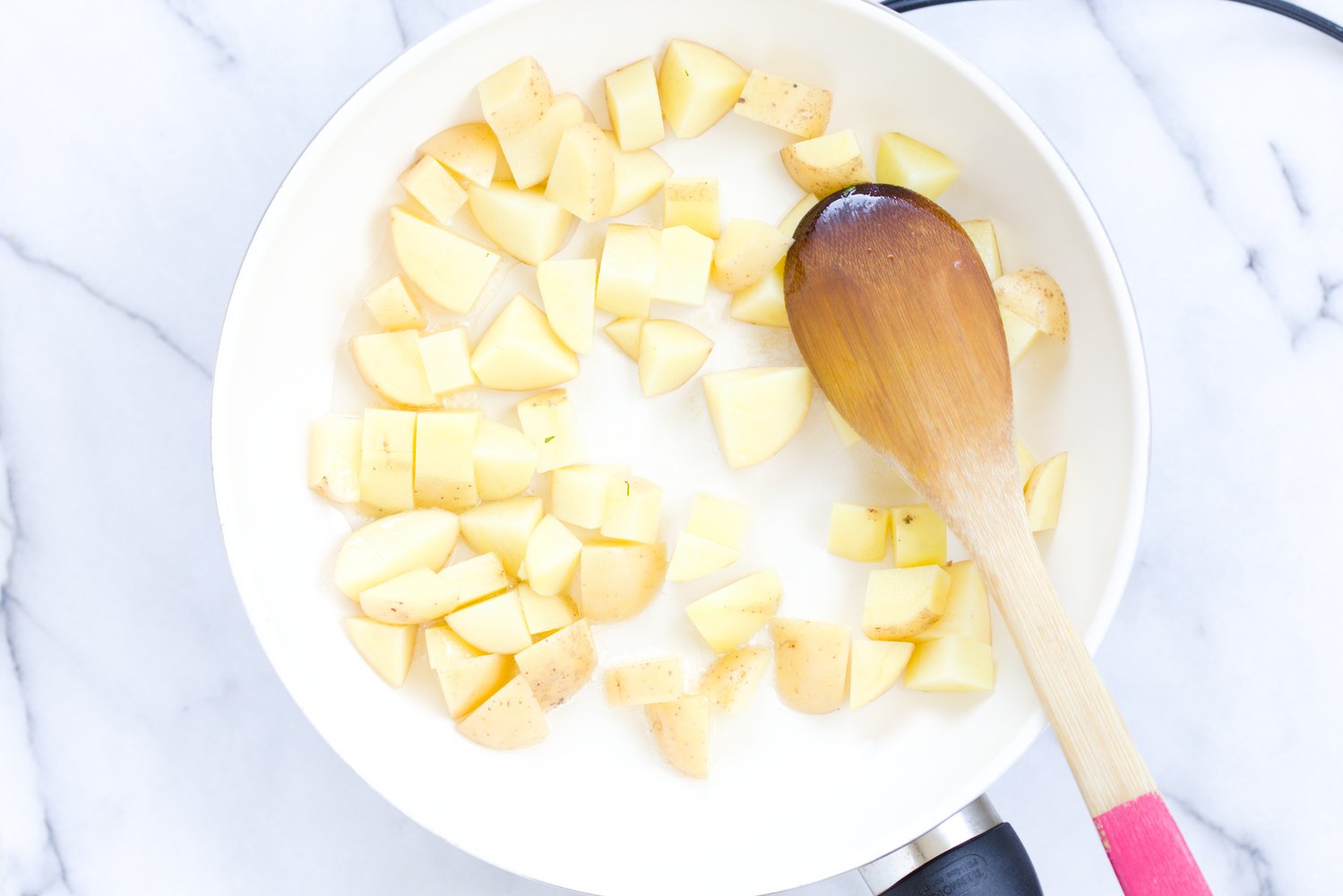 aloo matar potato cubes being sauteed in a skillet