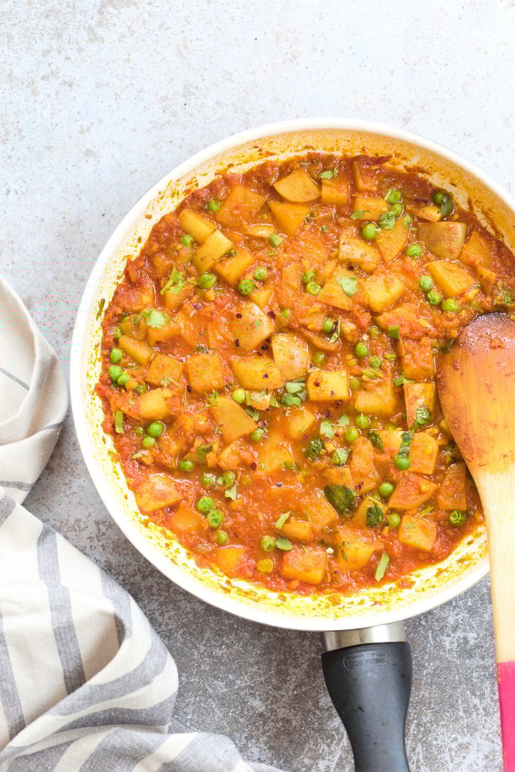 aloo matar overhead shot of a white skillet with vegan aloo matar with peas and potatoes