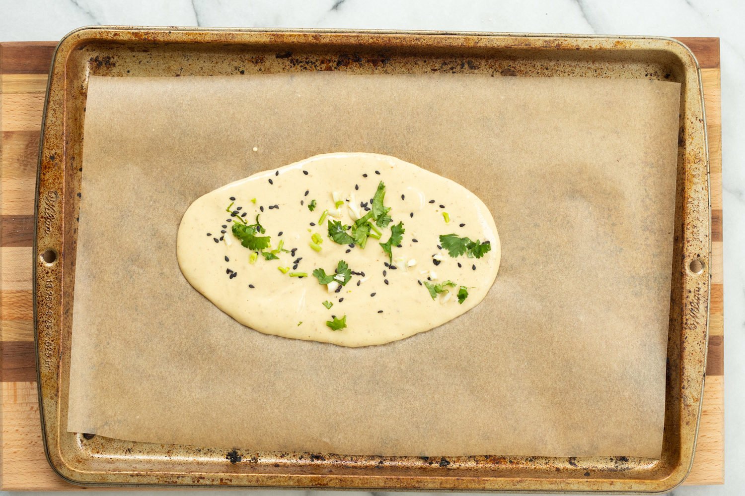 Batter for our Vegan Gluten Free Naan spread on parchment lined baking sheet