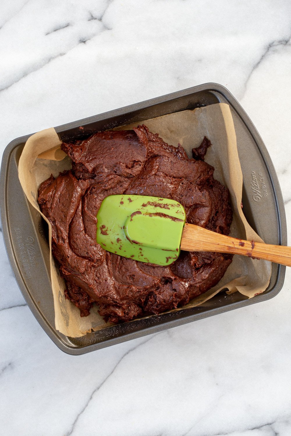 Batter of Our Vegan Chickpea Brownies in a parchment lined brownie pan