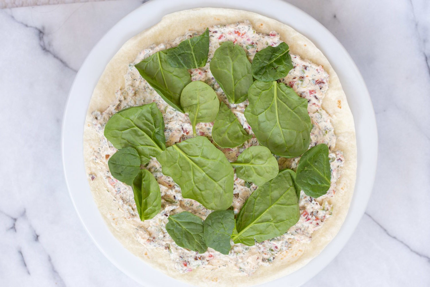 Dairy free Veggie Cream Cheese and Spinach spread on tortilla for our Vegan Tortilla Roll ups recipe