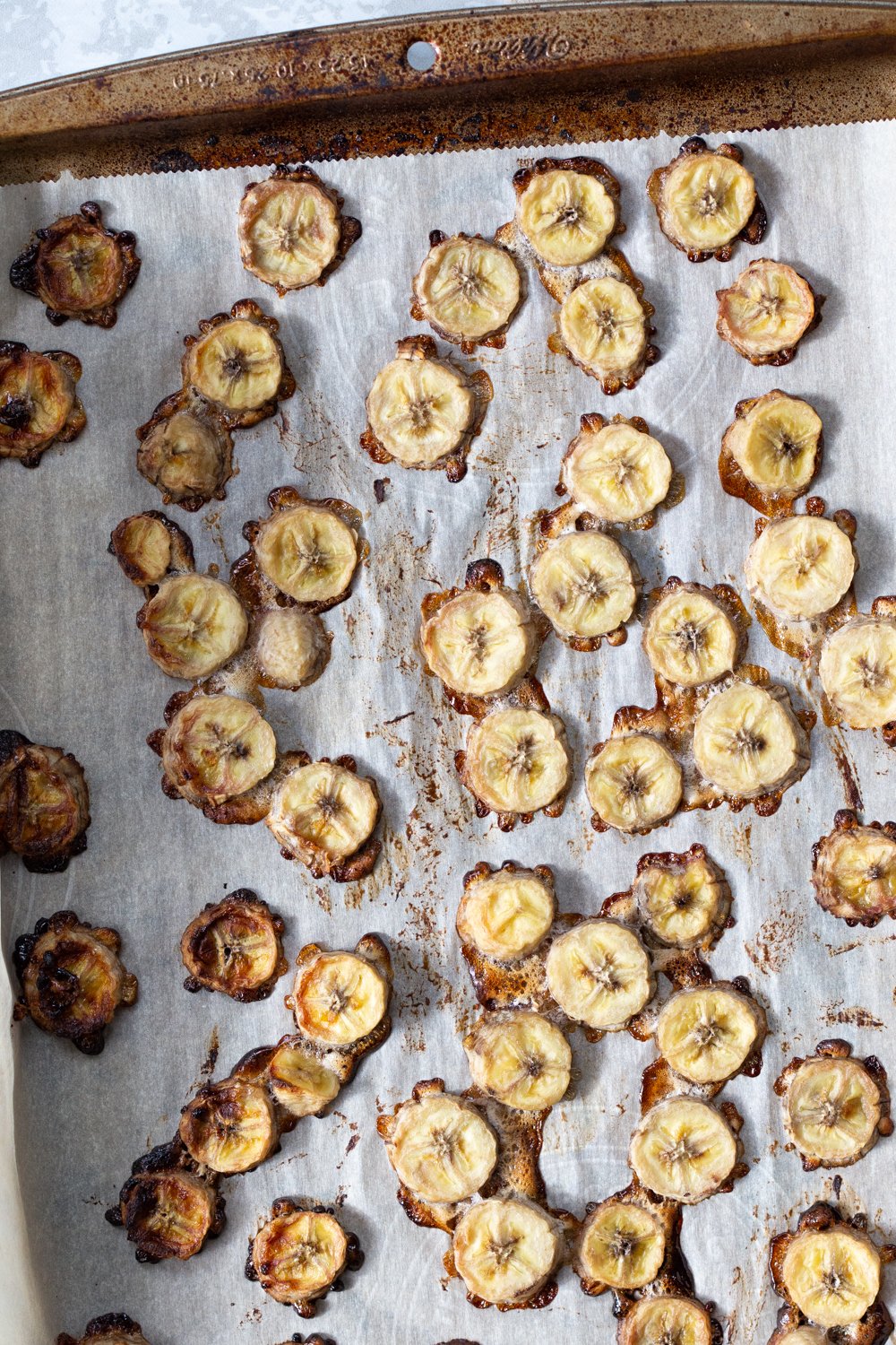 overhead shot of sliced bananas roasting on a baking sheet