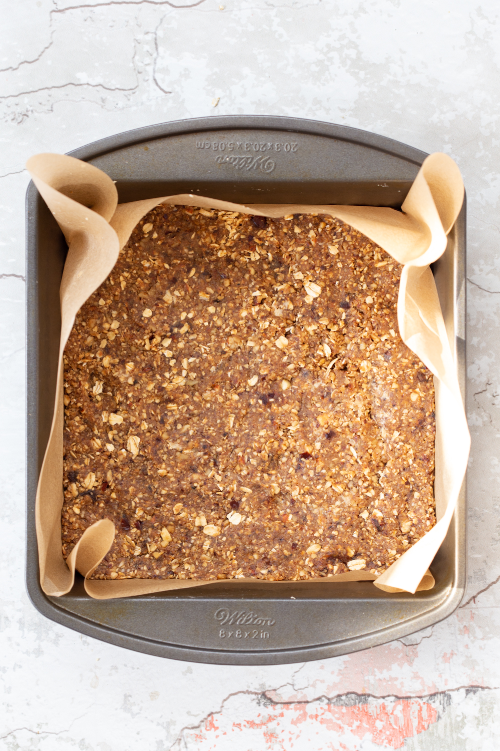 vegan granola bars  overhead shot of unbaked vegan banana granola bars in a metal baking pan