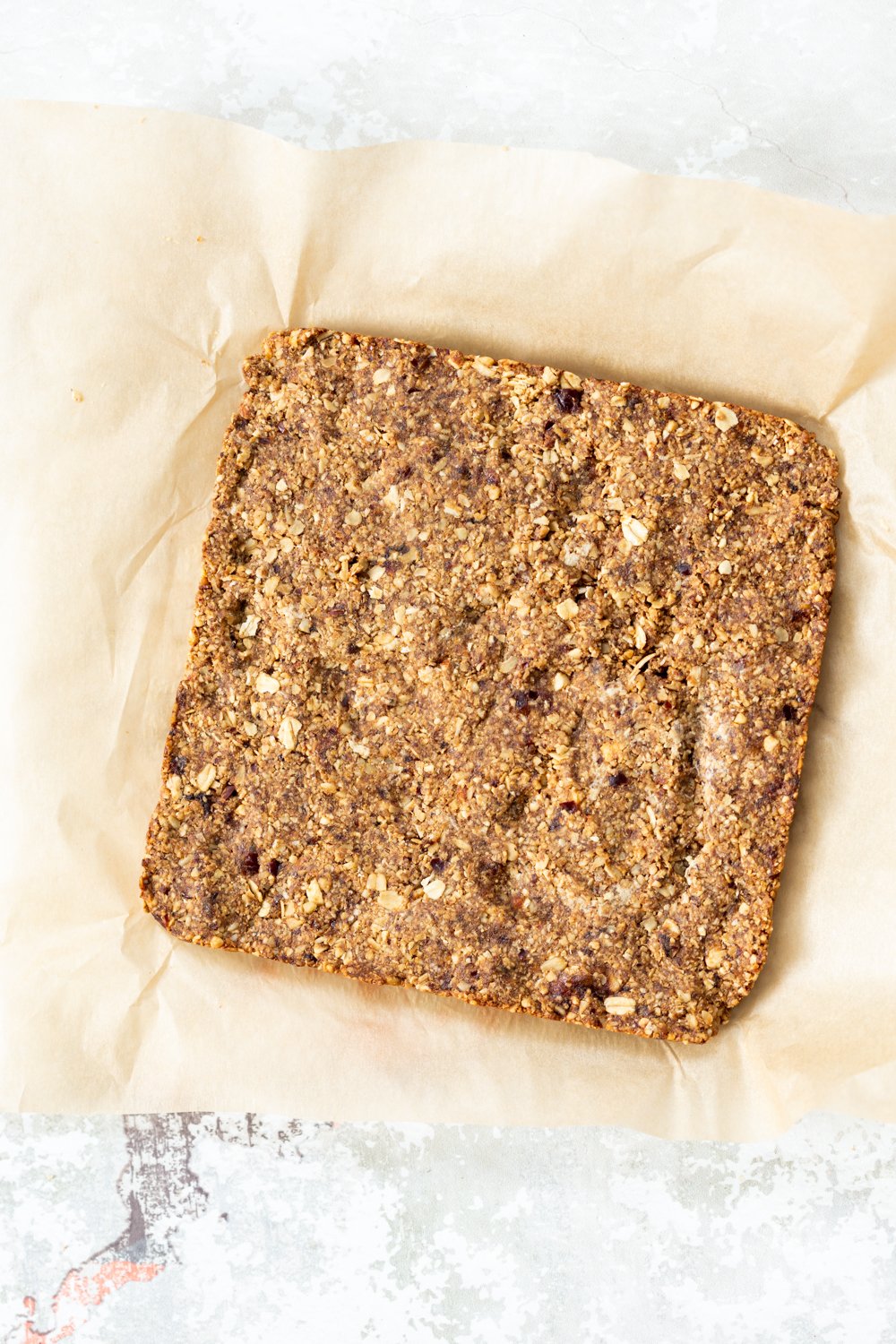 vegan granola bars  overhead shot of vegan banana granola bars on a sheet of baking paper ready to be cut